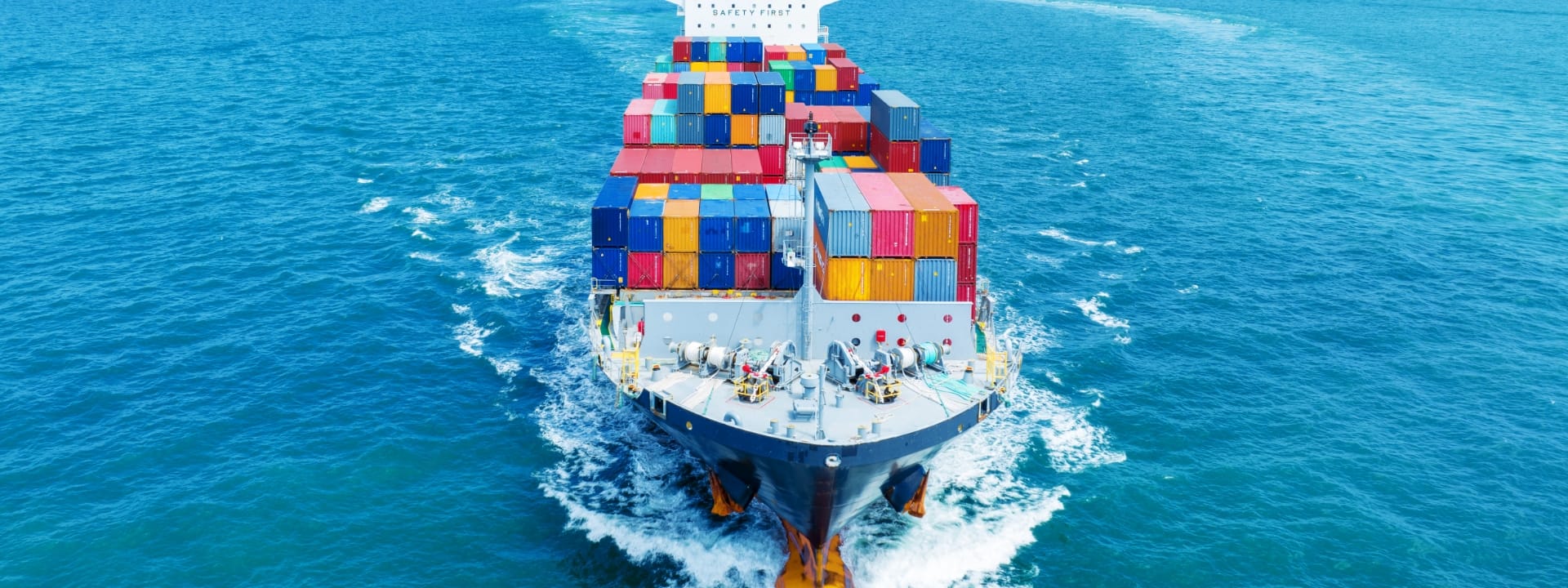 スライド画像：海を進む、大量にコンテナを積んだ船の写真